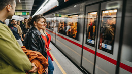 Eine Gruppe von Menschen steht an einer U-Bahnstation und wartet auf den Stillstand des Zuges.