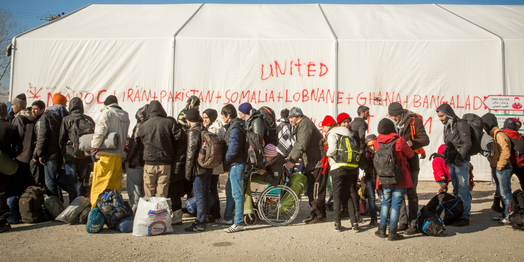 Flüchtlinge stehen im griechischen Flüchtlingslager Idomeni Schlange vor einem großen Zelt.