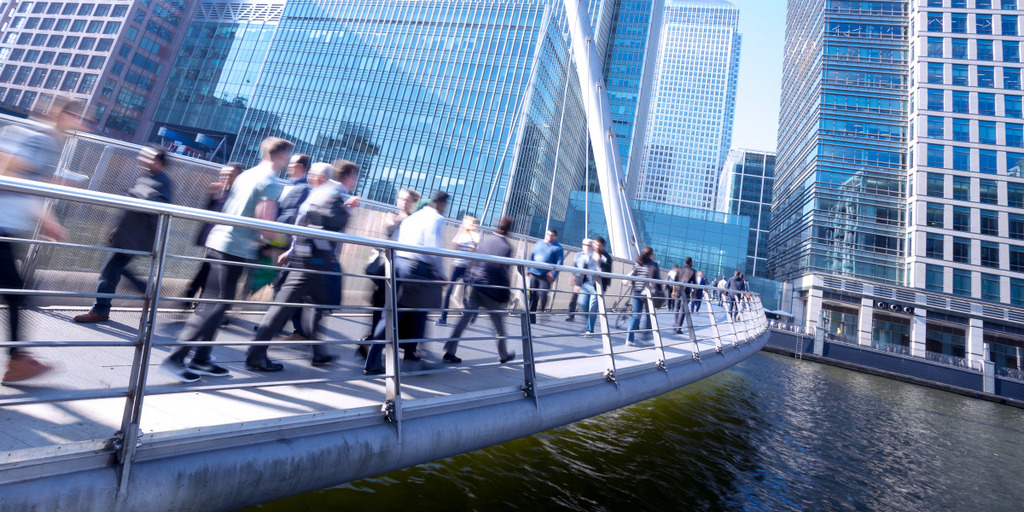 Several businesspeople walk across a bridge in the City of London, London's financial district.