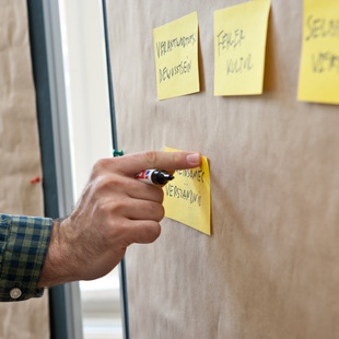 Nahaufnahme: 3 Post-its auf einer Metaplanwand