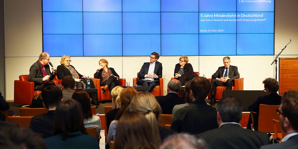 Personen auf Podium vor blauer Medienwand