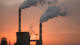 Two smoking chimneys of an industrial plant at dusk