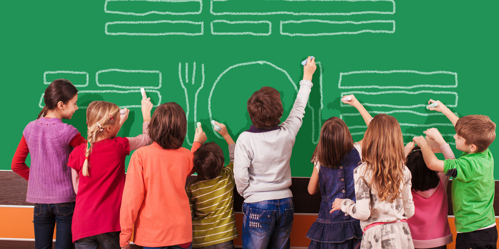 Eine Gruppe von neun Kindern mal mit Kreide auf die Schultafel.