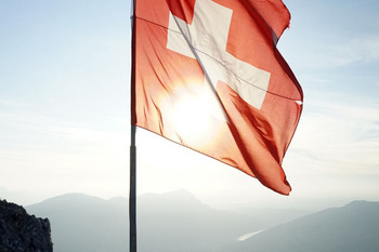 Two men standing next to a Swiss flag