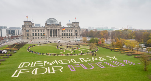 Schriftzug und Menschen auf dem Rasen vor dem Reichstagsgebäude