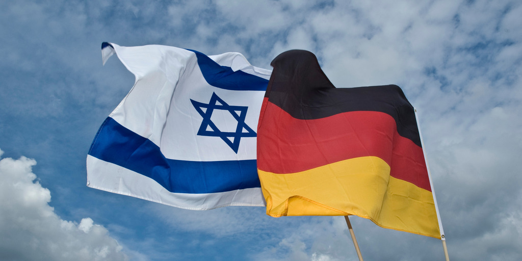 Eine israelische und eine deutsche Flagge wehen nebeneinander im Wind.