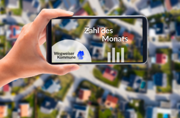 Im Hintergrund des Bildes wird eine Stadt von oben gezeigt. Im Vordergrund hält eine Hand ein Handy. Auf dem Display des Handys ist ein Foto von der Stadt, das Logo Wegweiser Kommune, ein Balkendiagramm und der Aufschrift Zahl des Monats.