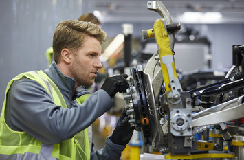 Selbstbewusster mittlerer erwachsener Ingenieur, der das Fahrgestell eines Autos in der Autoindustrie untersucht.