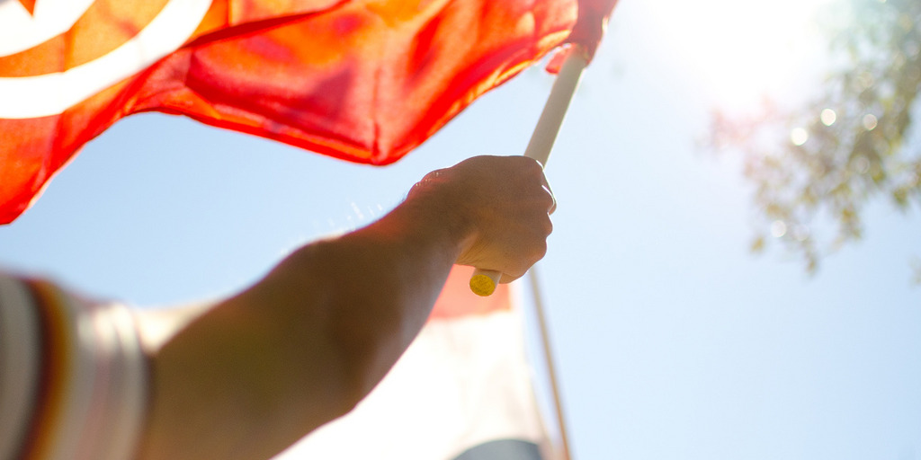 Arm eines Mannes mit tunesischer Fahne, die im Wind weht.