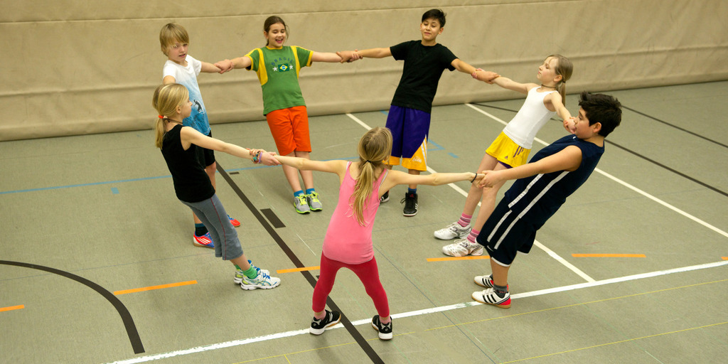 Schüler des Montessori-Gymnasiums Köln bilden in einer Turnhalle einen Kreis.