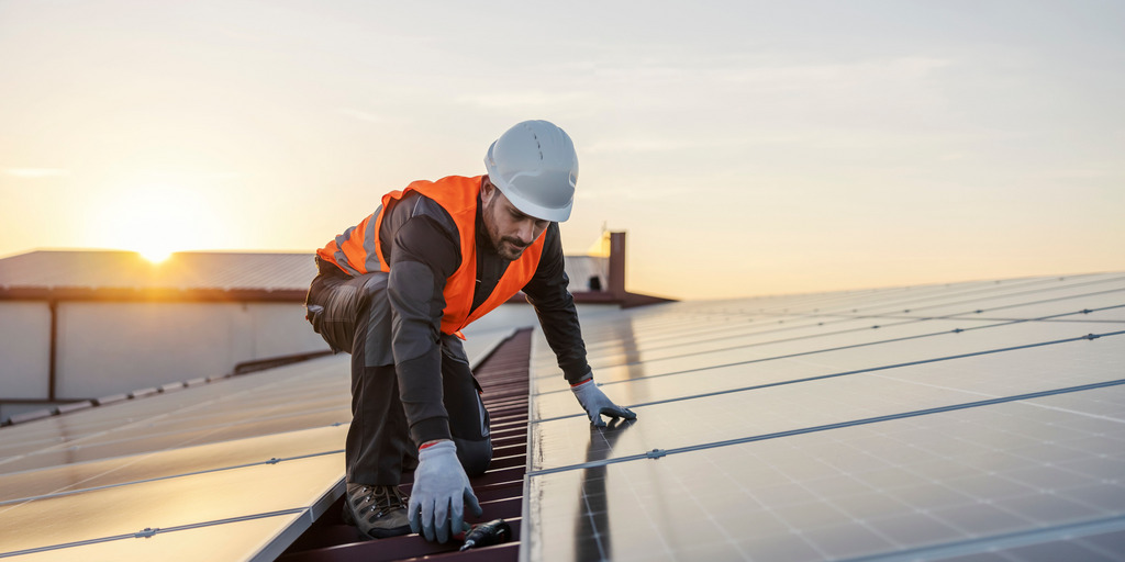Mann auf Dach installiert Solarzellen