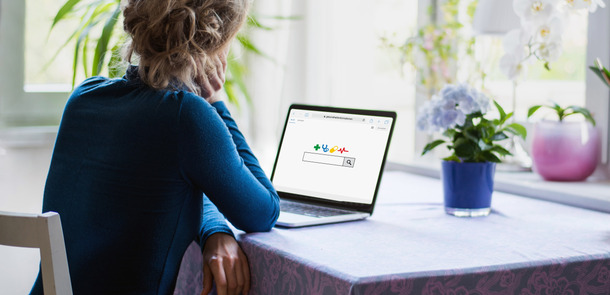 A woman is looking on a laptop on which she has opened a search engine website.