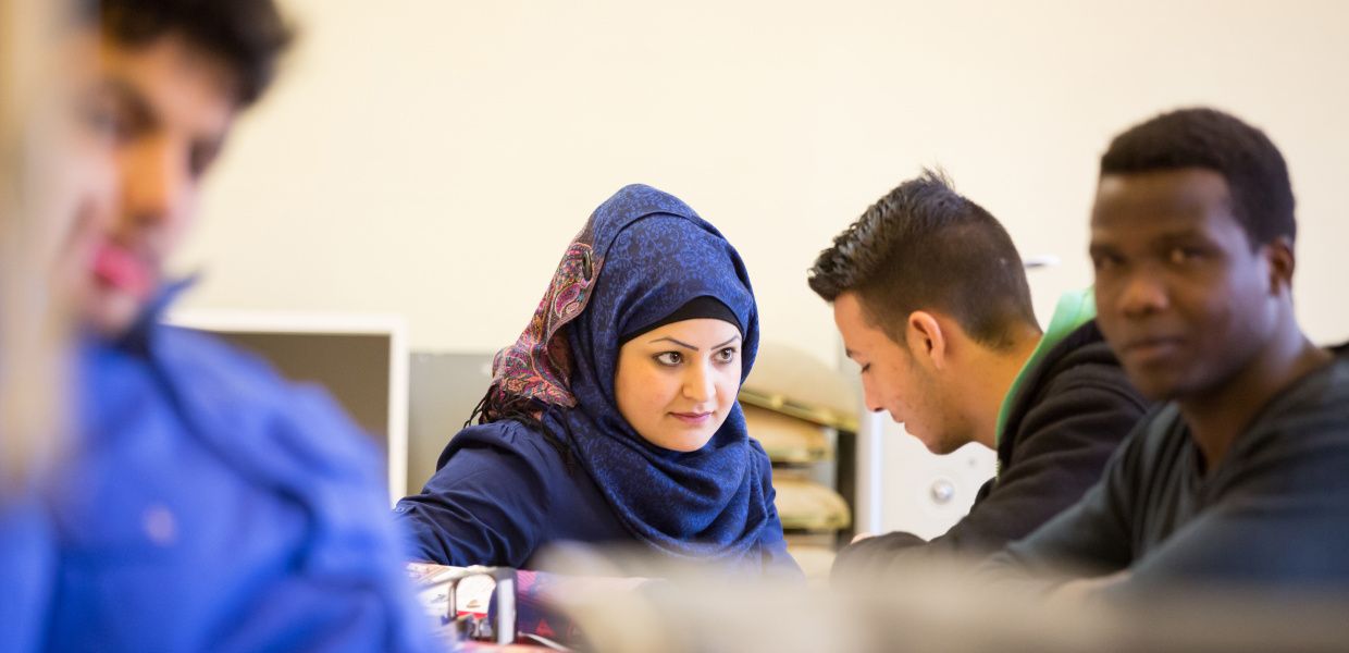 (© Valeska Achenbach) Vier Flüchtlinge - eine Muslima mit Kopftuch und drei Afrikaner - sitzen in einer Klasse der Berufsschule Lüchow und diskutieren.
