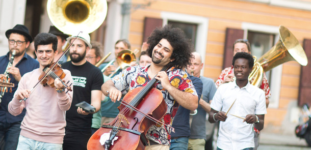 Musiker der Gruppe Banda Internationale ziehen mit verschiedenen Instrumenten durch die Straßen, während sie Musik machen.Musiker der Gruppe Banda Internationale ziehen mit verschiedenen Instrumenten durch die Straßen, während sie Musik machen.
