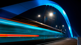 Beleuchtete Straßenbahnbrücke bei Nacht. Straßburg. Fahrende Straßenbahn.
