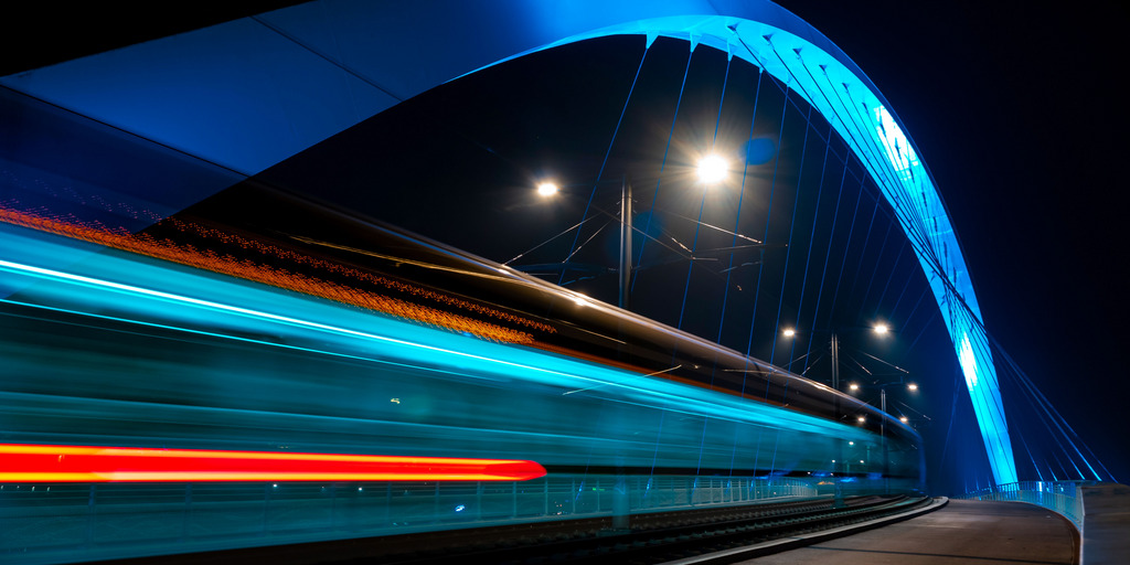 Beleuchtete Straßenbahnbrücke bei Nacht. Straßburg. Fahrende Straßenbahn.