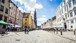 Auf dem Foto wird eine Straße in Flucht nach Hinten gezeigt. Die Straße besteht aus Kopfsteinpflaster. Links und Rechts stehen alte Häuser. Im Hintergrund ist eine Kirche zu sehen.