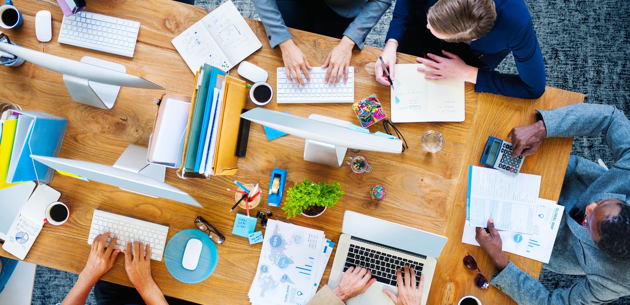 (© Shutterstock/Rawpixel.com) Mehrere Personen arbeiten an einem Tisch.