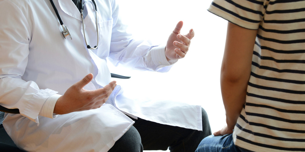 Arzt spricht gestikulierend mit Patient im Ringel-Shirt.
