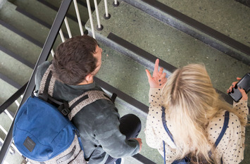 2 Srudenten gehen im Treppenhaus der Universität die Stufen hoch
