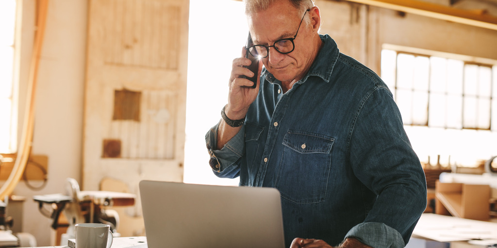 Mann arbeitet am Laptop und telefoniert dabei