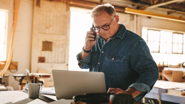 Mann arbeitet am Laptop und telefoniert dabei