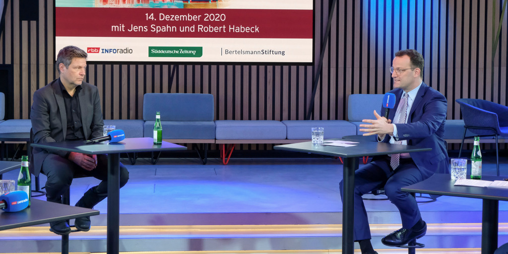 Grünen-Bundesvorsitzender Robert Habeck und Bundesgesundheitsminister Jens Spahn sitzen sich in einem Studio des Rundfunks Berlin-Brandenburg beim "Polittalk aus der Hauptstadt" an weit auseinanderstehenden Einzeltischen gegenüber. Jens Spahn hält ein Mikrofon in der Hand und spricht, während Robert Habeck zuhört.
