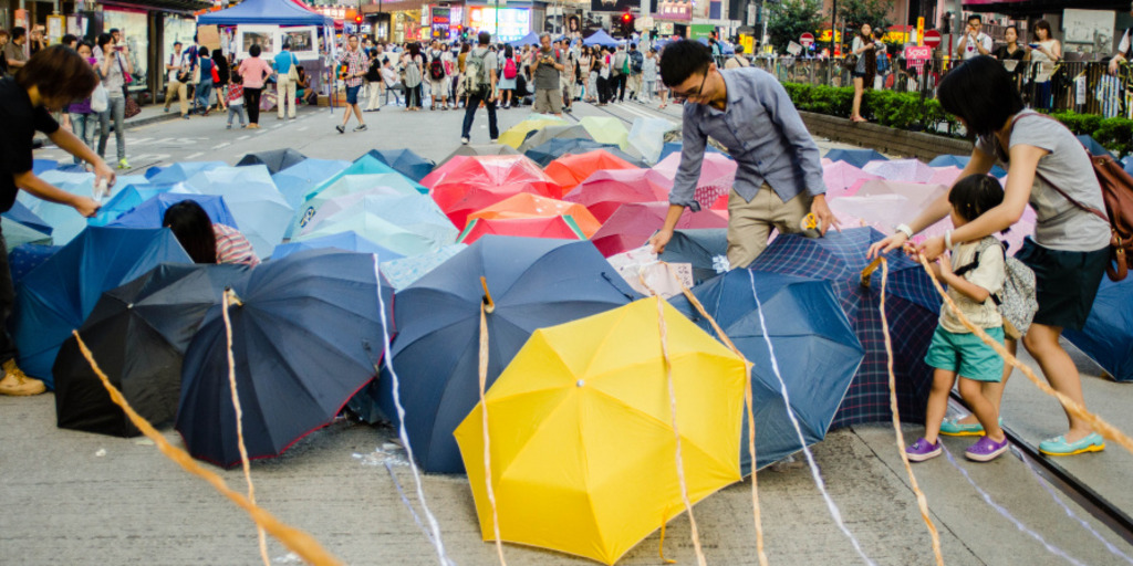 Demonstranten stellen im Rahmen der Proteste in Hongkong im Oktober 2014 Regenschirme auf eine Straße.