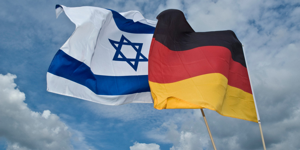 Israelische und deutsche Flagge wehen nebeneinander im Wind.