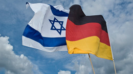 Israelische und deutsche Flagge wehen nebeneinander im Wind.