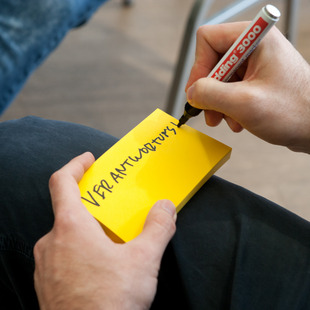 Nahaufnahme: jemand schreibt auf einen Post-it "Verantwortung"