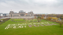 Schriftzug und Menschen auf dem Rasen vor dem Reichstagsgebäude
