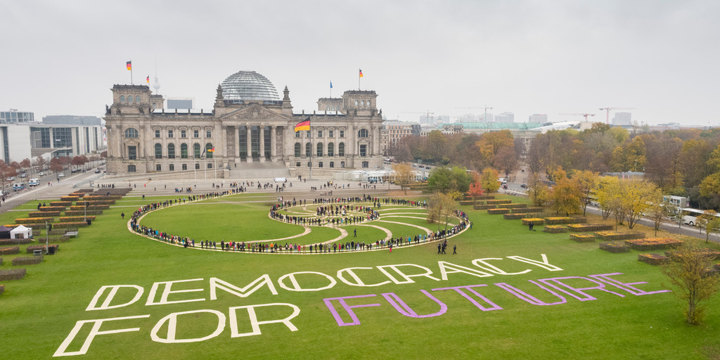 Schriftzug und Menschen auf dem Rasen vor dem Reichstagsgebäude