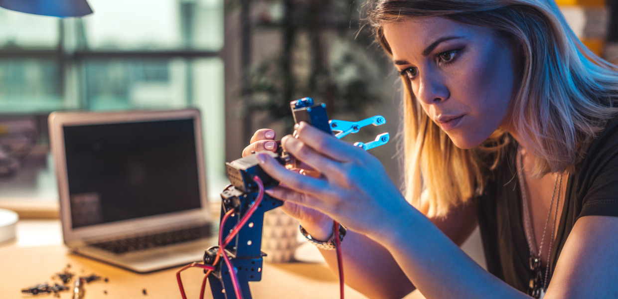 (© Getty Images/iStockphoto/Georgijevic) Junge Frau arbeit in einem Werkraum für Technik an einer Roboterhand.