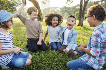 Auf einer Wiese fröhlich sitzende Kinder