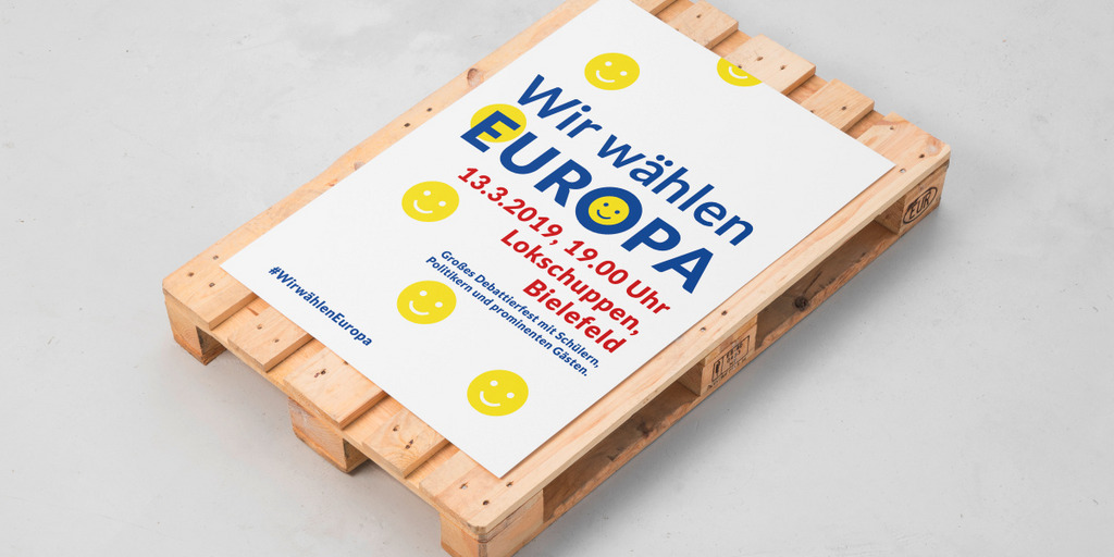 Auf einer Euro-Palette, die normalerweise zum Transport genutzt wird, liegt das Plakat mit der Ankündigung der Veranstaltung "Wir wählen Europa" am 13. März 2019 in Bielefeld