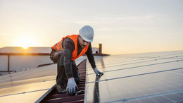 Mann auf einem Dach installiert Solarzellen