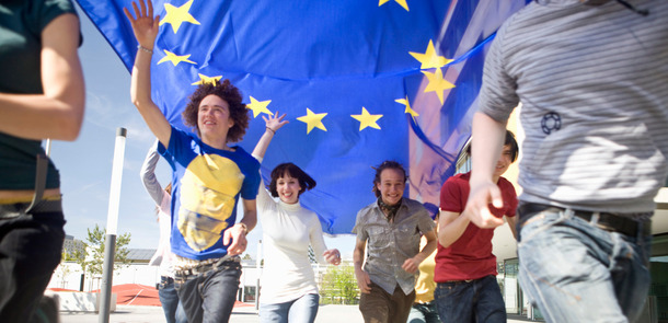 Einige Jungendliche laufen, die EU-Flagge in der Luft haltend, durch München.