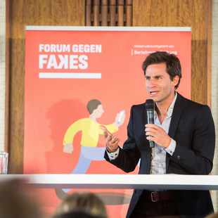 Moderator spricht vor Banner