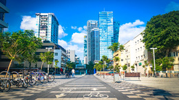 Blick auf eine Straße in Tel Aviv. Auf dem Boden sind breite Fahrradwege. Im Hintergrund viele Hochhäuser.