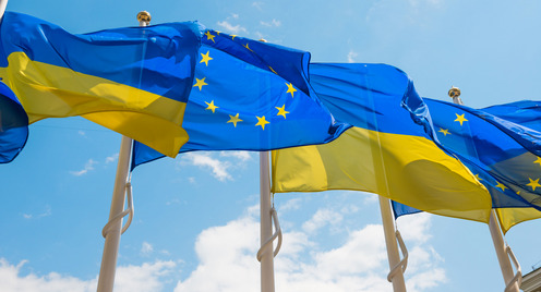 Nebeneinander aufgereiht wehen ukrainische Flaggen und Flaggen der EU an Fahnenmasten.