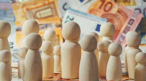 Spielfiguren aus Holz vor Euro-Scheinen