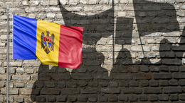 [Translate to English:] Shadows of demonstrating people projected on a wall, on the left side the Moldovan flag