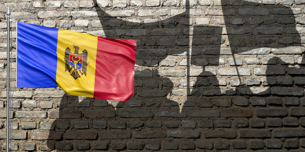[Translate to English:] Shadows of demonstrating people projected on a wall, on the left side the Moldovan flag