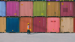 Viele bunte Container, die übereinander und nebeneinander gestapelt in einem Containerhafen stehen.