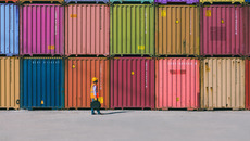 Engineer man with yellow crash helmet and worker west checking cargo freights in front of colorful cargo container stacks in shipping port.(© Getty Images/iStockphoto.com/serts)