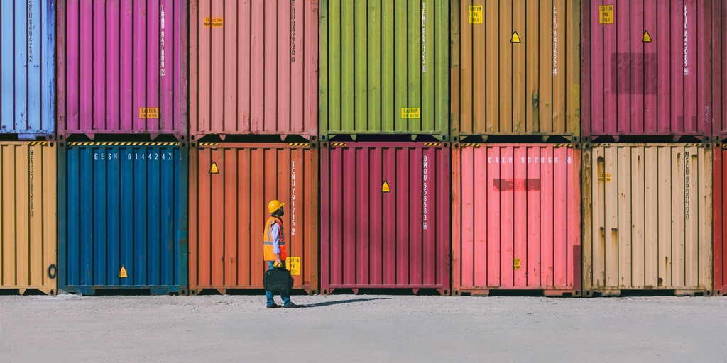 Viele bunte Container, die übereinander und nebeneinander gestapelt in einem Containerhafen stehen.