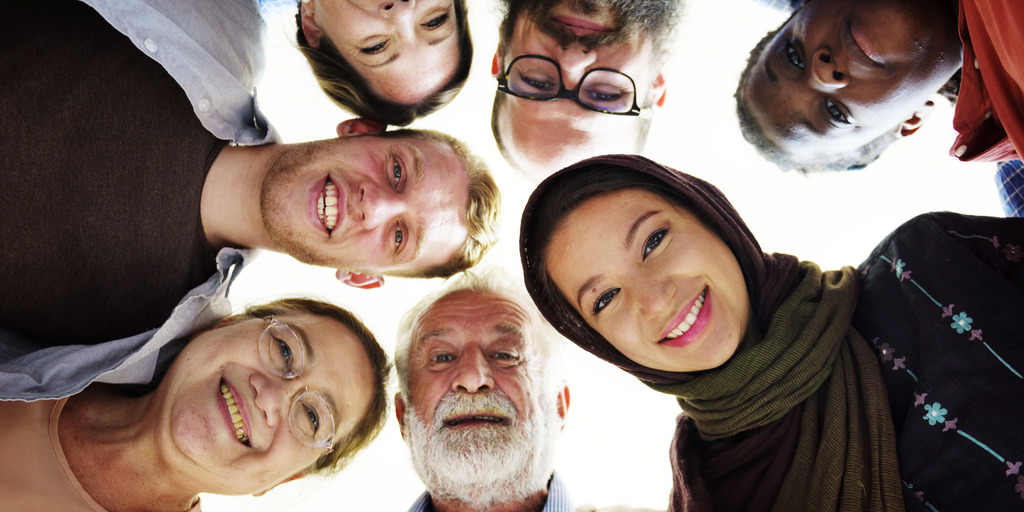 unterschiedlich aussehende Menschen schauen von oben in die Kamera