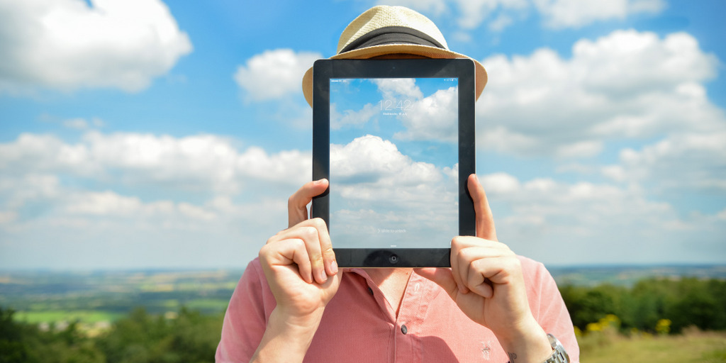 Porträtbild eines Mannes vor Wolkenhimmel, an Stelle des Gesichts ein durchsichtiges Tablet