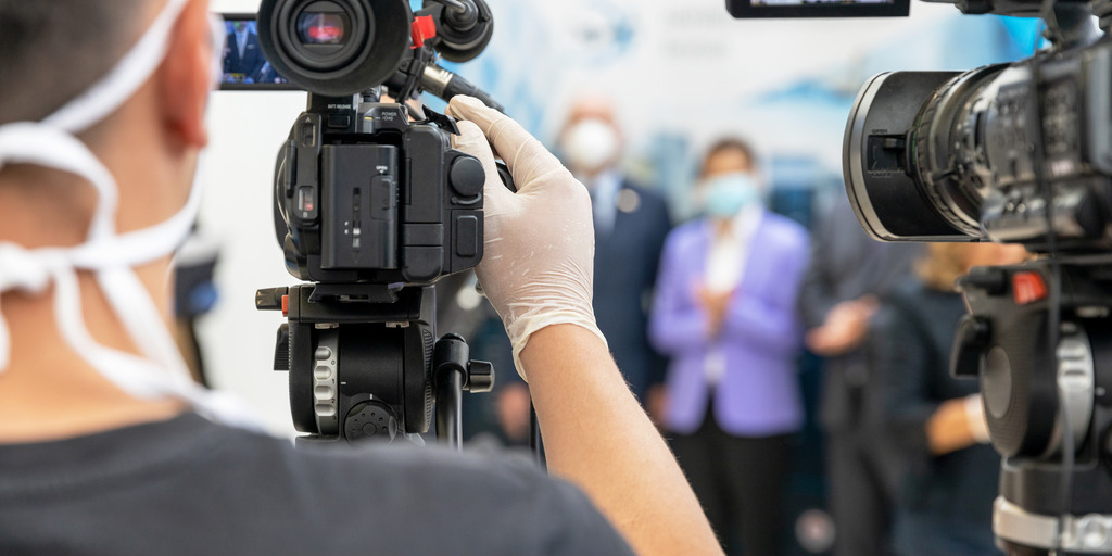[Translate to English:] Blick aus der Sicht der Kameras, die eine Pressekonferenz während der Corona-Pandemie halten.